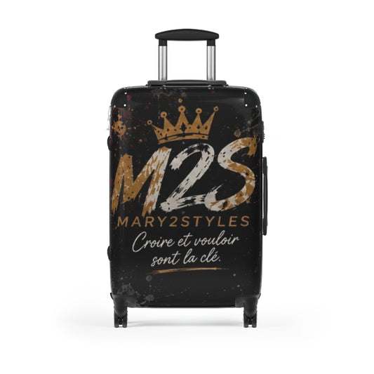 Valise noire avec couronne, « M2S », « MARY2STYLES » et le texte « Croire et vouloir sont la clé. »